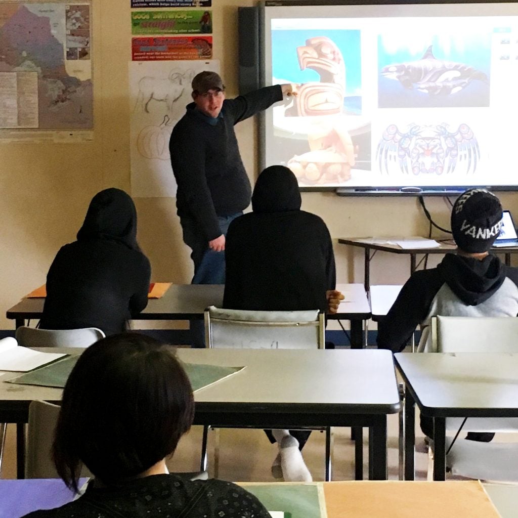 Teacher in front of SMART board with students listening